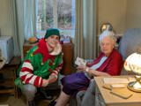 A young person dressed all Christmasy talking to an older lady 