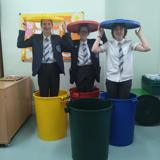 The group standing in recycling bins