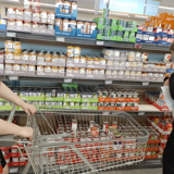 The group pushing a trolley and looking at food in a supermarket aisle 